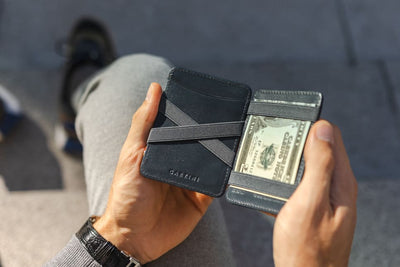 A hand holding the wallet with money inside.